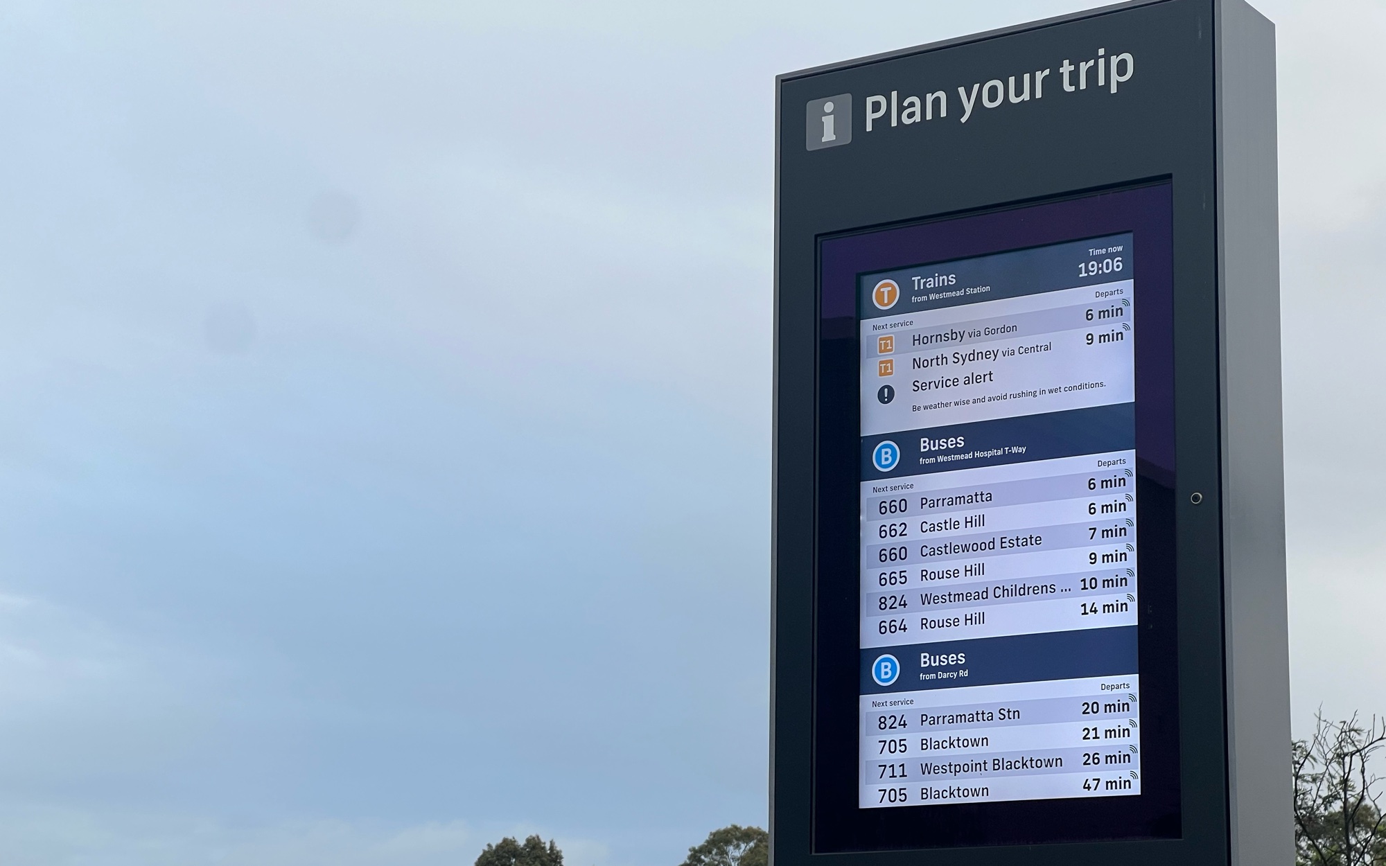 An AnyTrip Displays totem showing live train and bus departures at Westmead.